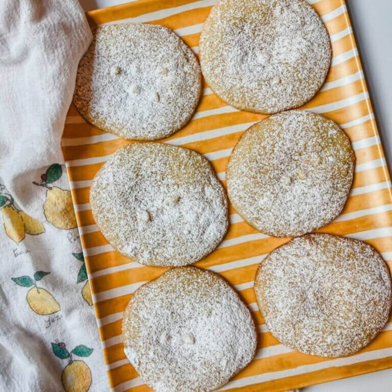 overhead view of 6 panera lemon drop cookies on a yellow striped platter.