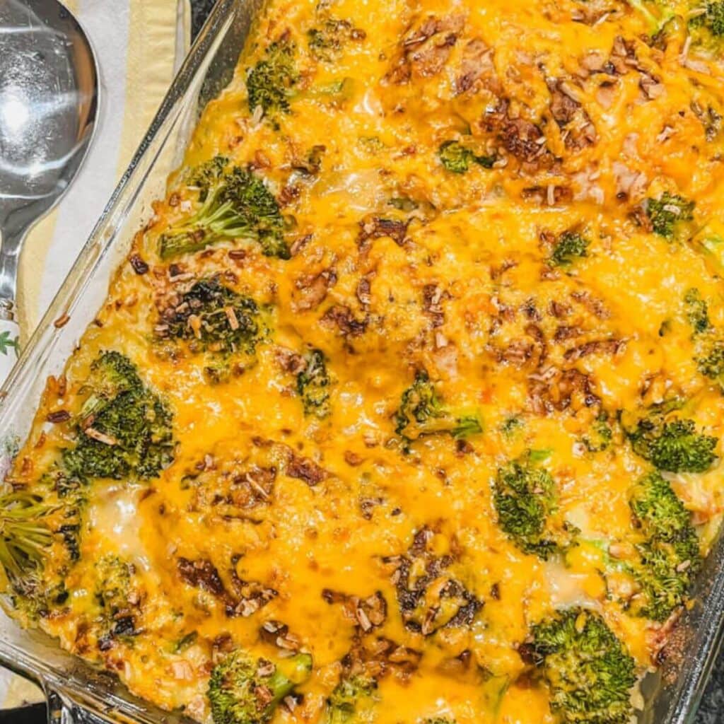 close up image of tiktok chicken and rice casserole with a silver serving spoon next to the baking dish.