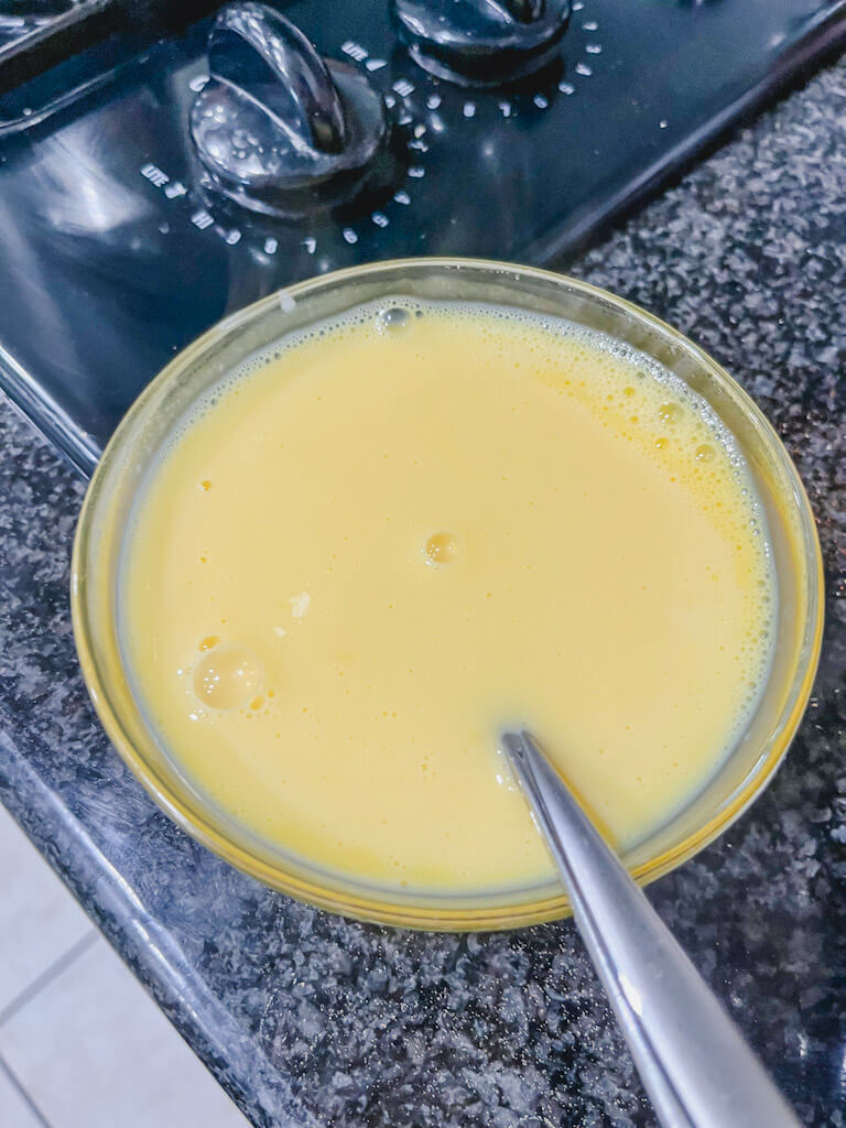 milk and egg yolks mixed together in a small glass bowl.