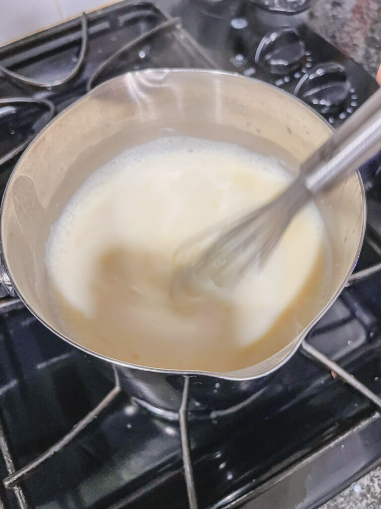 pudding mixture mixed together in a small saucepan on the stovetop.