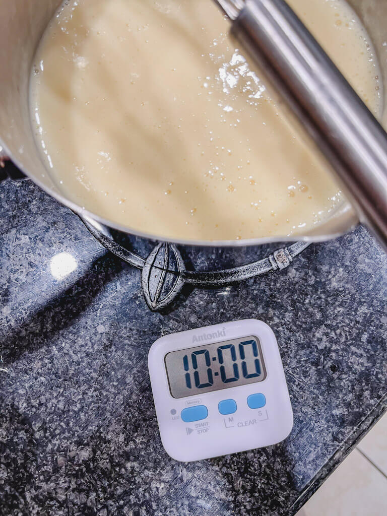 a timer showing 10 minutes next to a saucepan to allow the mixture to cool down.
