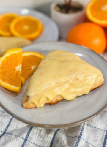panera orange scone on a plate with orange slices.