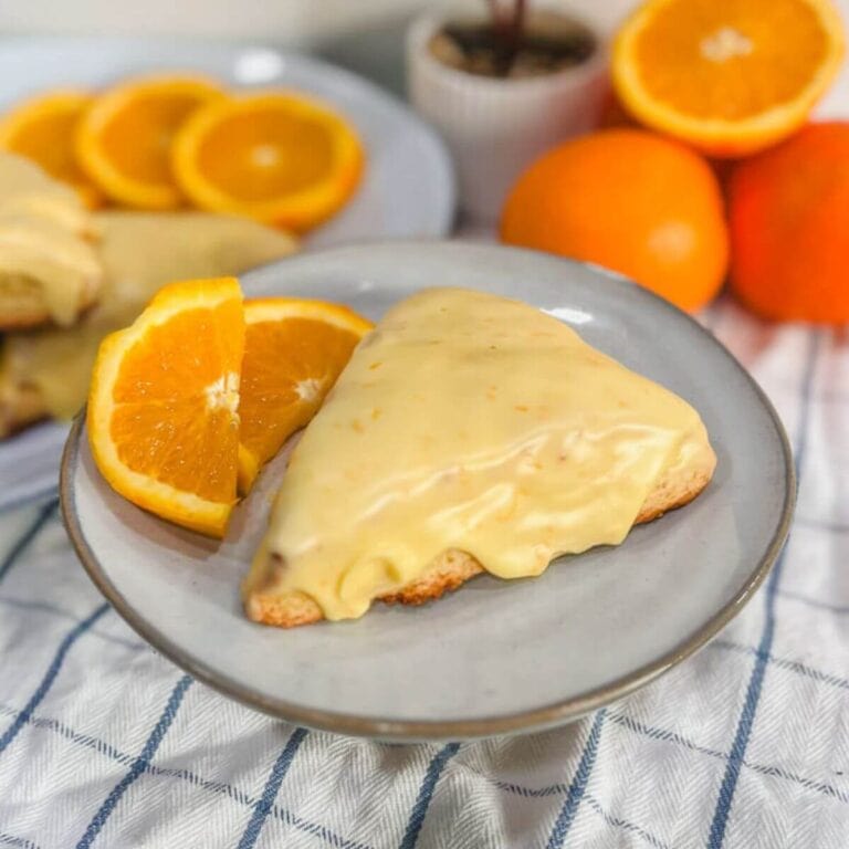 panera orange scone on a plate with orange slices.