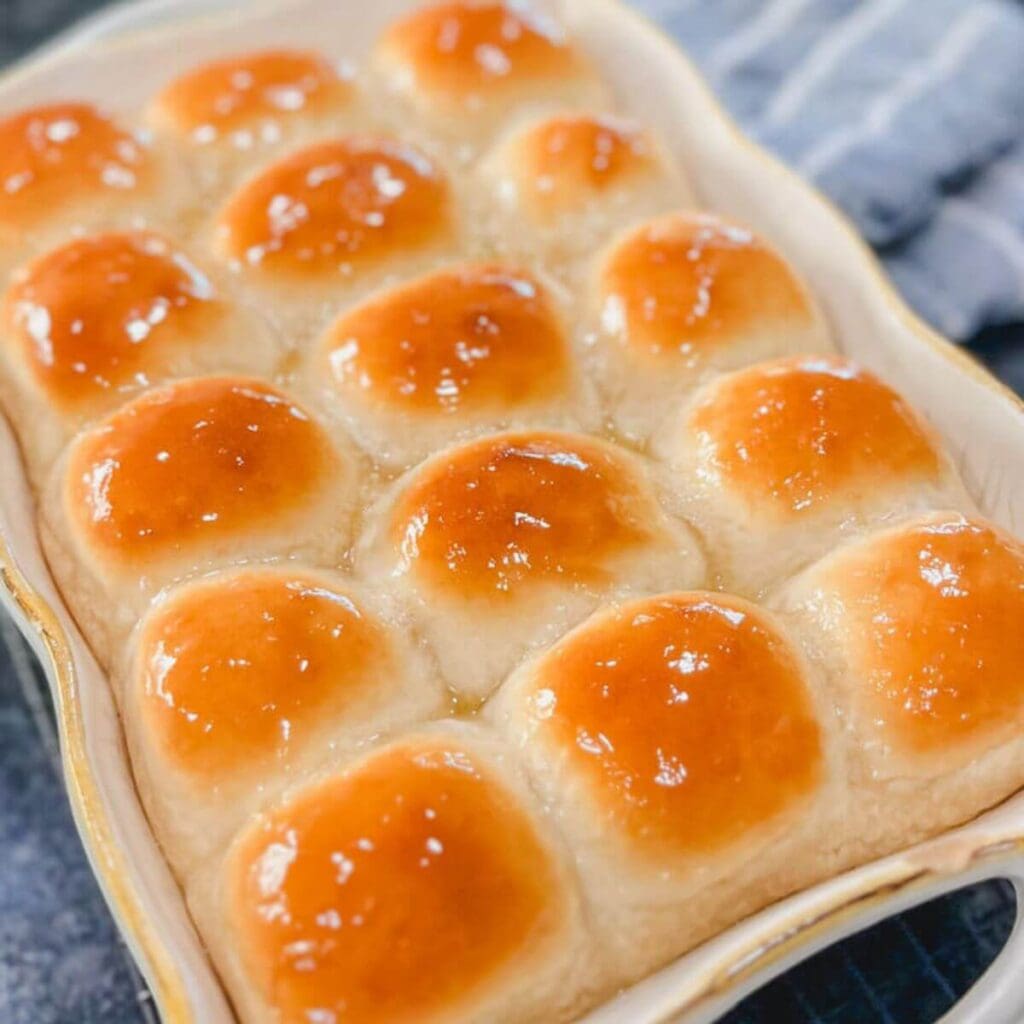 close up of one hour honey butter dinner rolls in a baking dish.