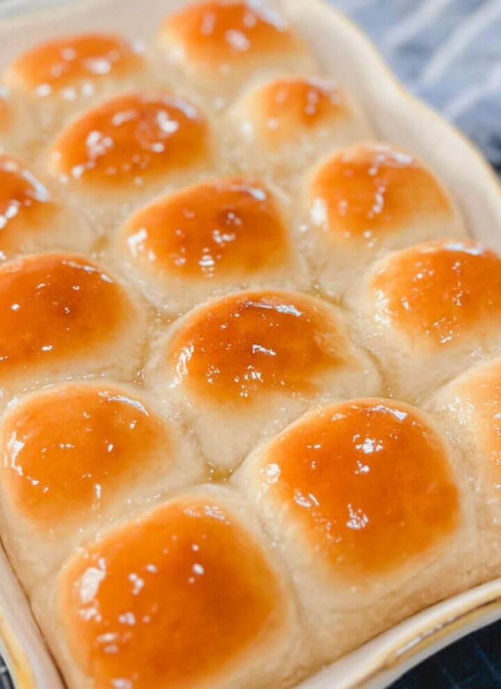 close up of one hour honey butter dinner rolls in a baking dish.