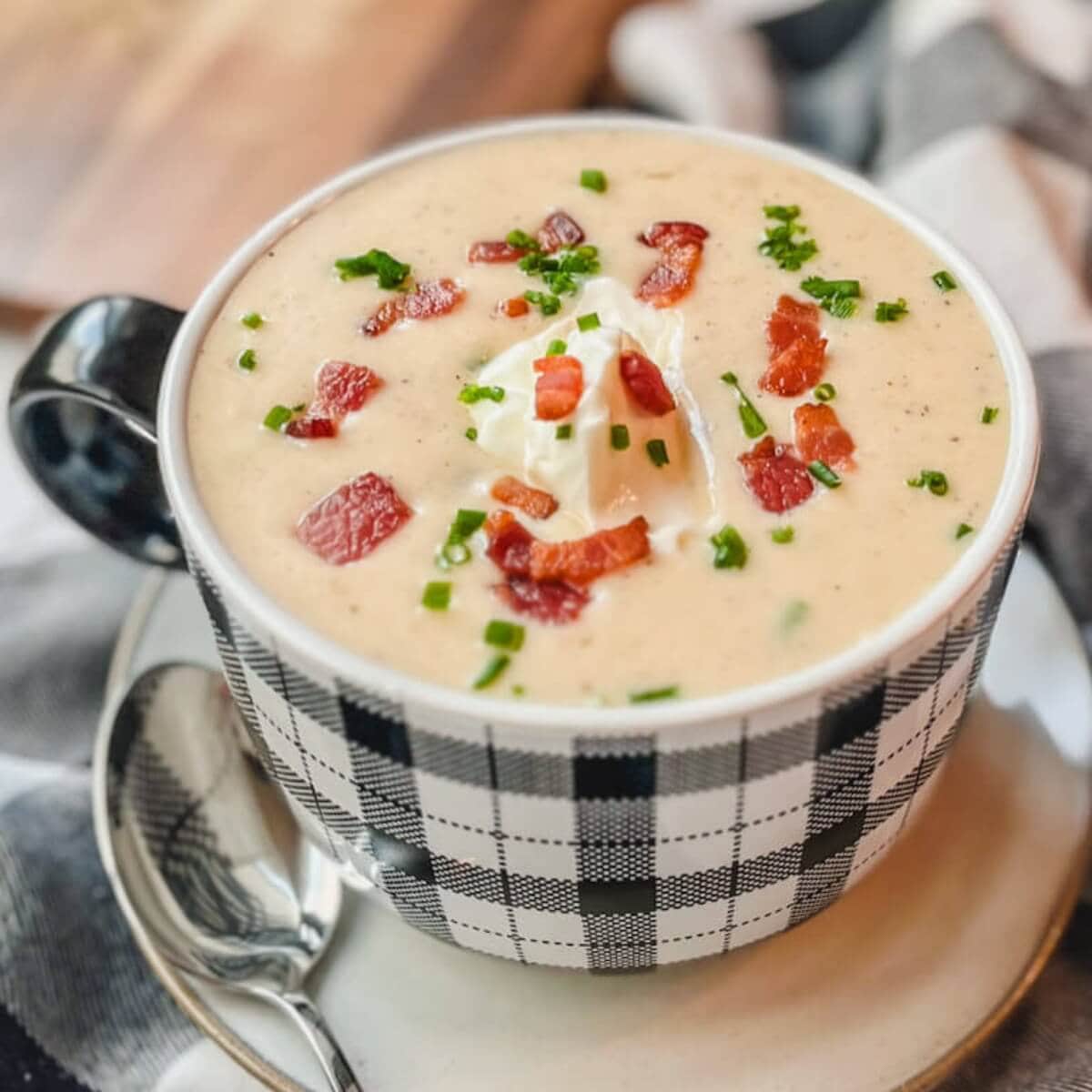 a large mug of panera bread baked potato soup on a white plate.