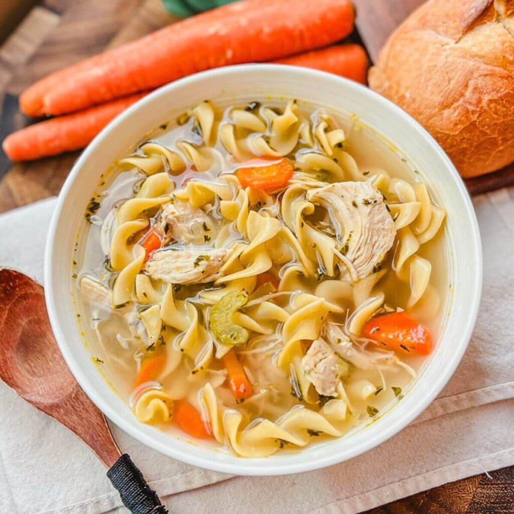 a bowl of panera bread chicken noodle soup on a beige tea towel.