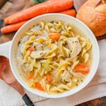 a bowl of panera bread chicken noodle soup on a beige tea towel.