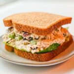 starbucks chicken salad on whole wheat bread placed on a white plate.
