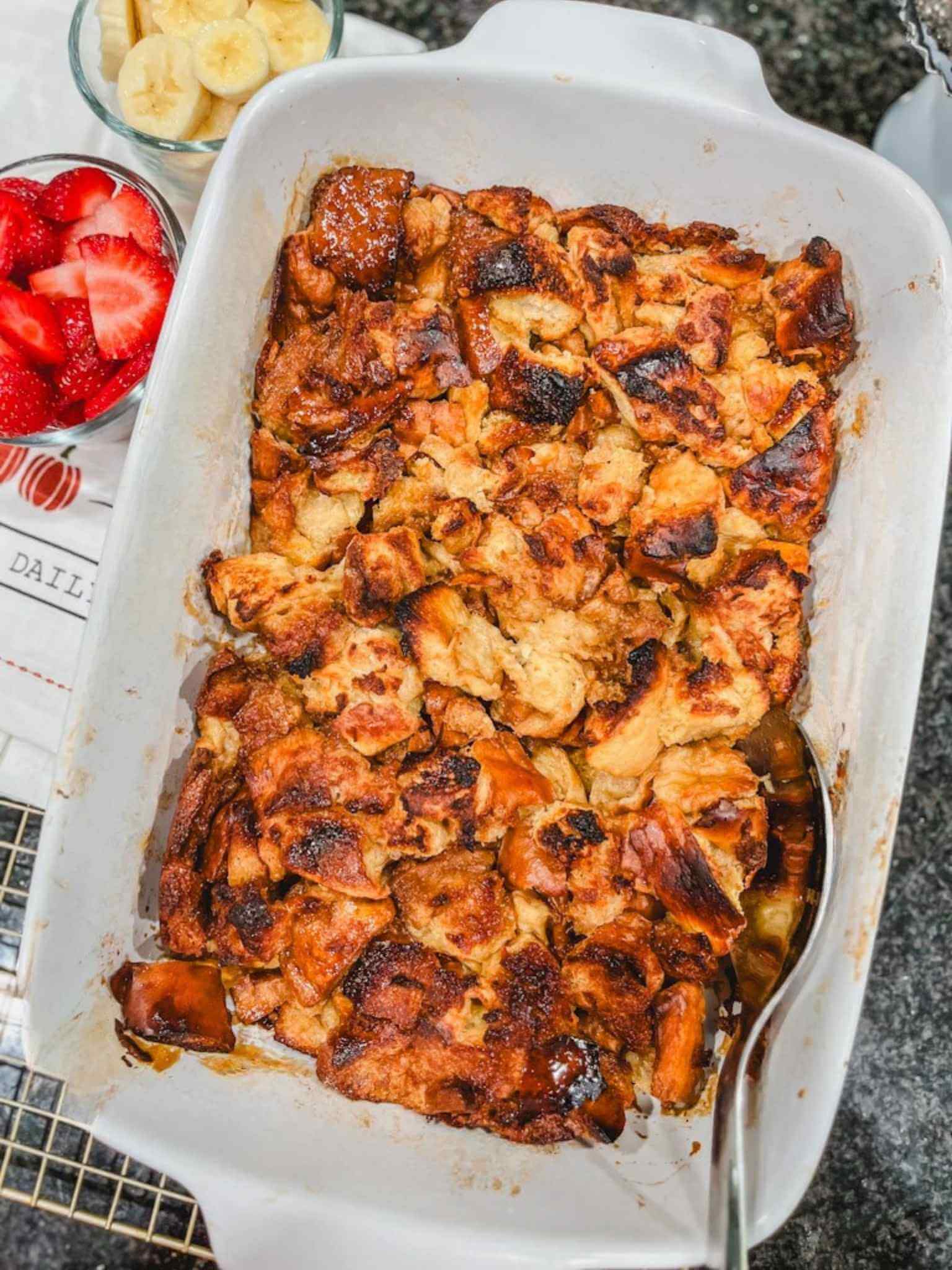 overhead picture of overnight French toast casserole next to strawberries and bananas.