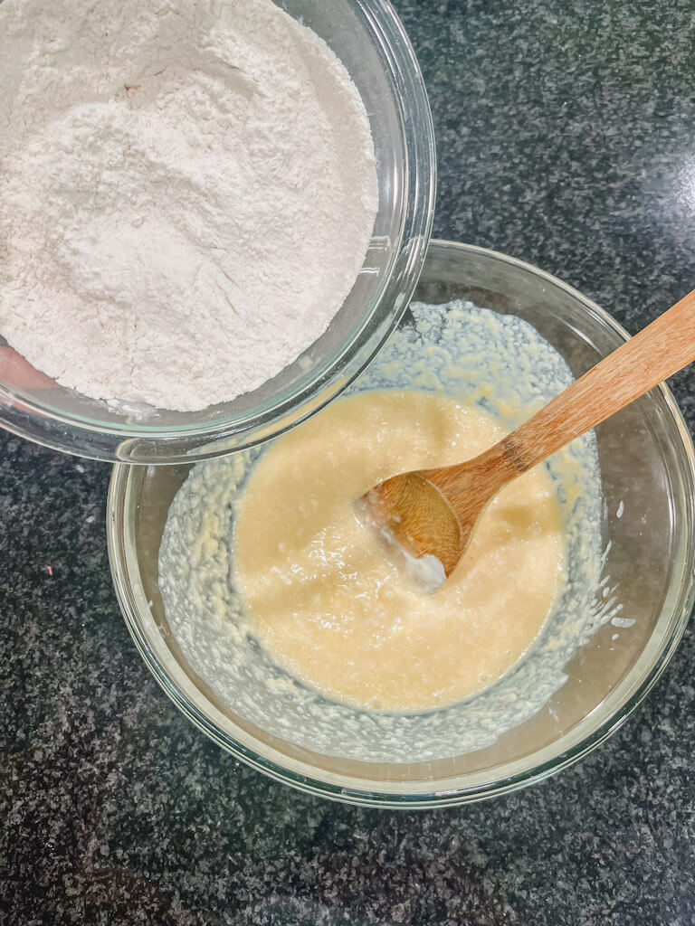 a bowl with the dry ingredients being held over the wet ingredients for strawberry streusel muffins.