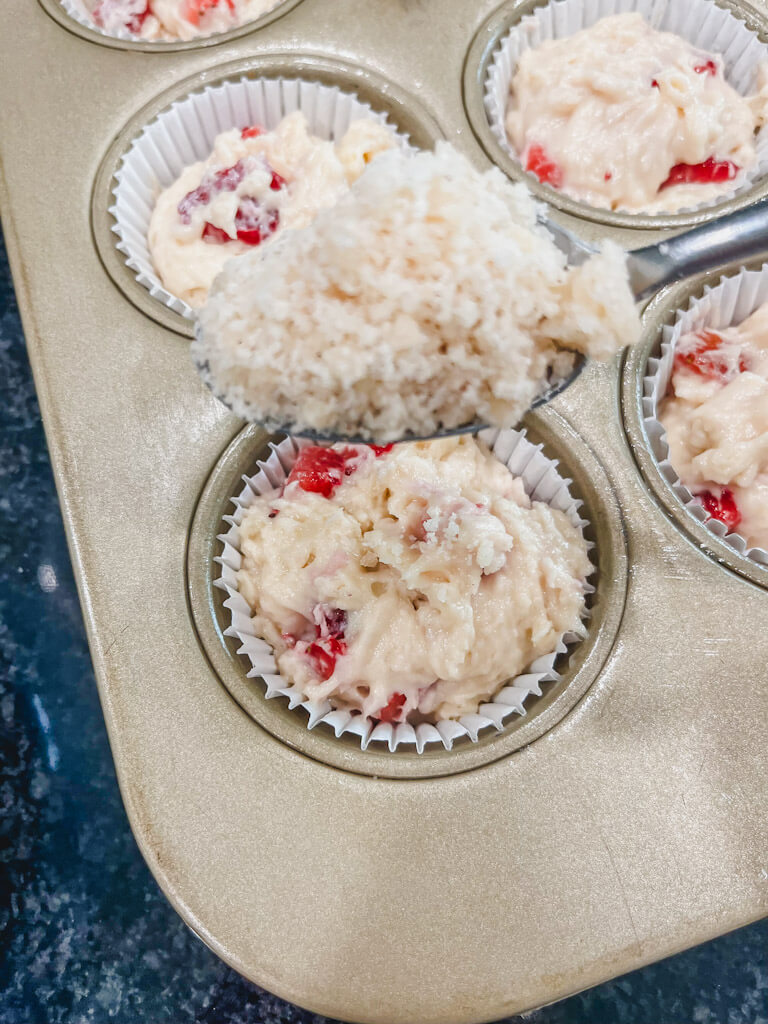 a spoon holding streusel crumble over the top of the muffins.