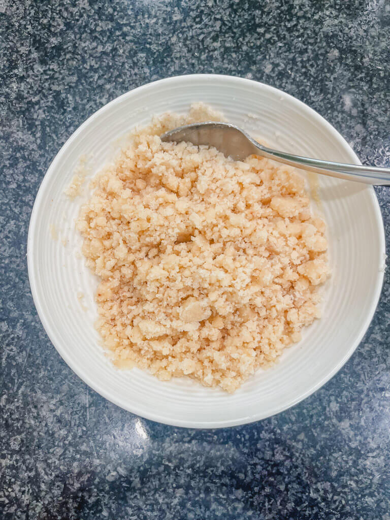 streusel crumble in a white bowl with a spoon.
