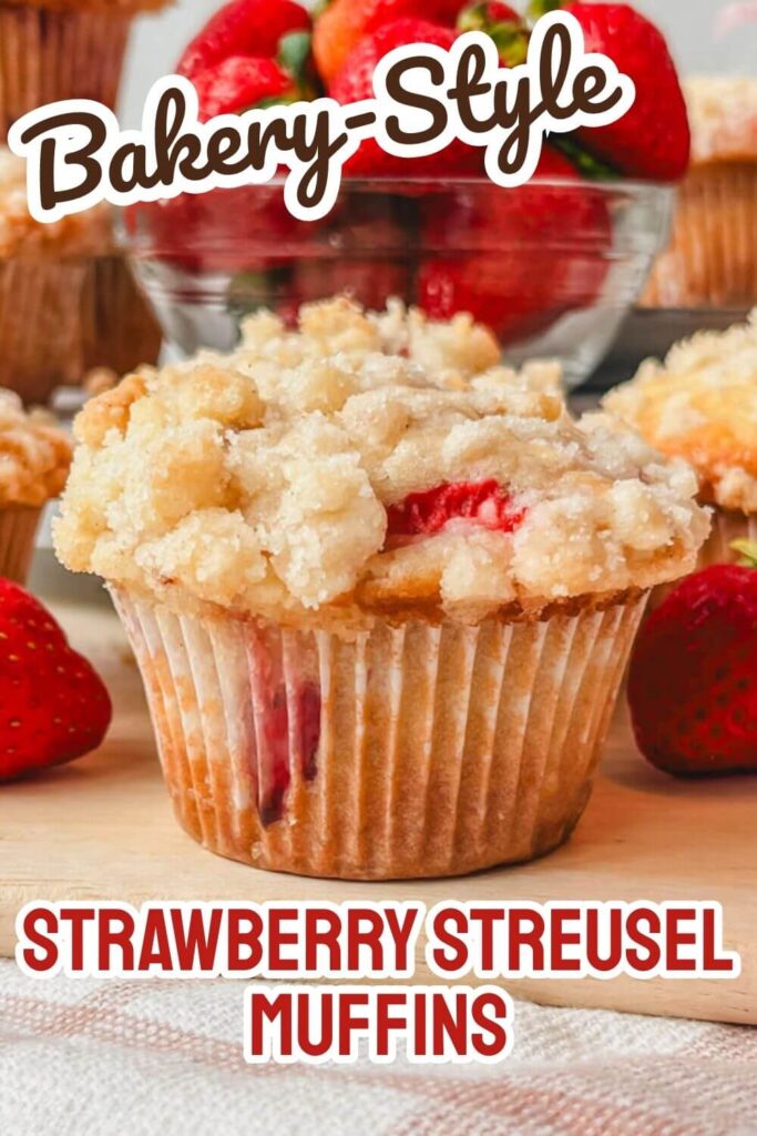 a picture of a strawberry streusel muffin on a wooden cutting board.