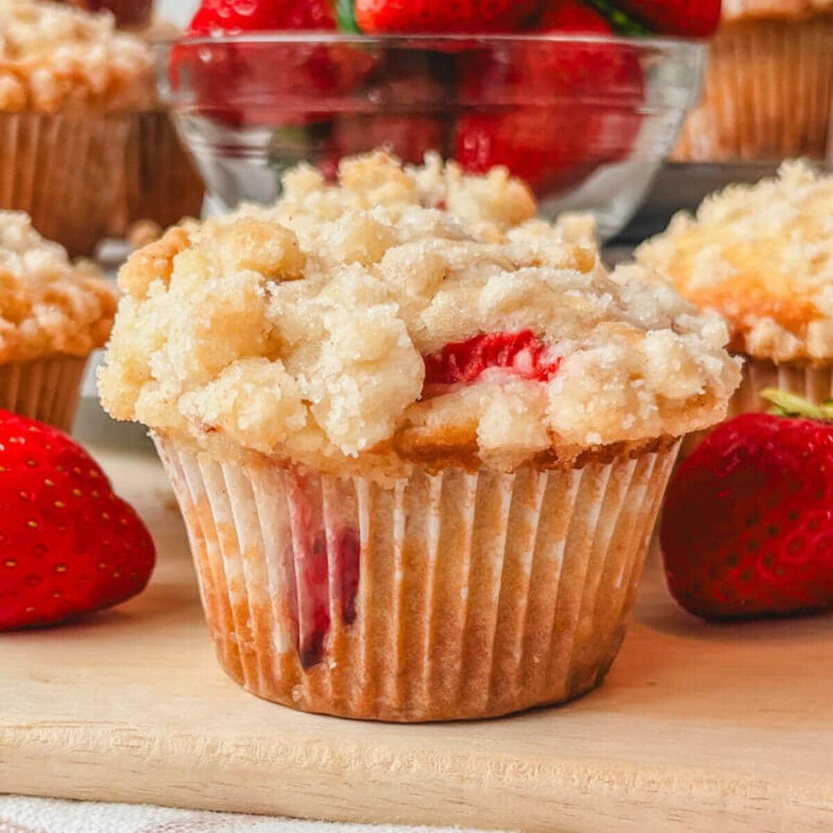 close up of a bakery-style strawberry muffin on a cutting board.