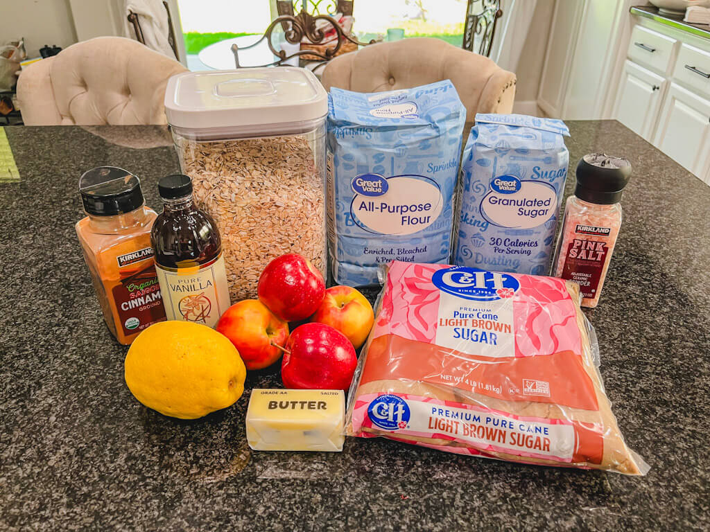 ingredients for apple crisp recipe laid out on a black counter.
