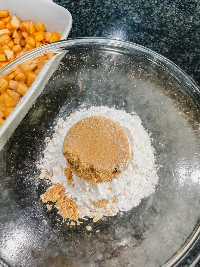 light brown sugar added to the bowl of flour and oats for apple crisp recipe.