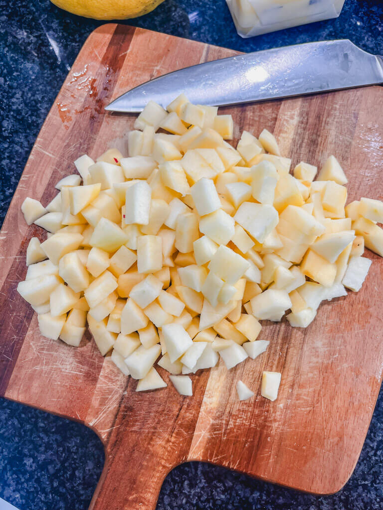 diced apples on a cutting board for apple crisp recipe with oats.