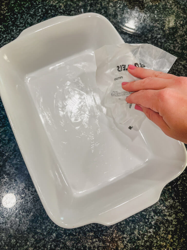 taking wax paper from butter and greasing a casserole dish with it for apple crisp.