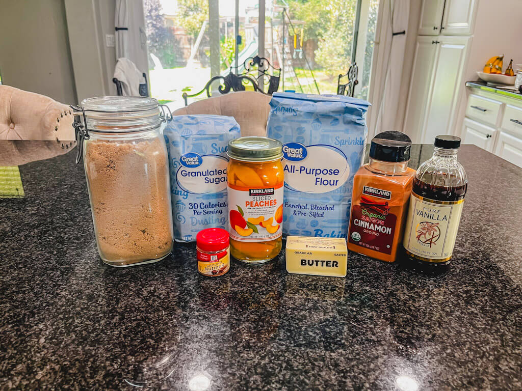 ingredients for peach crumble without oats laid out on a black counter.