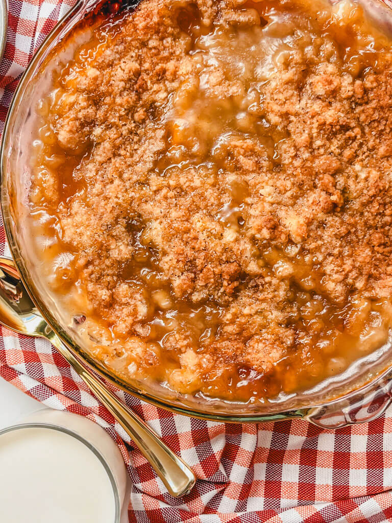 overhead view of peach crumble without oats after baking on a striped kitchen towels.