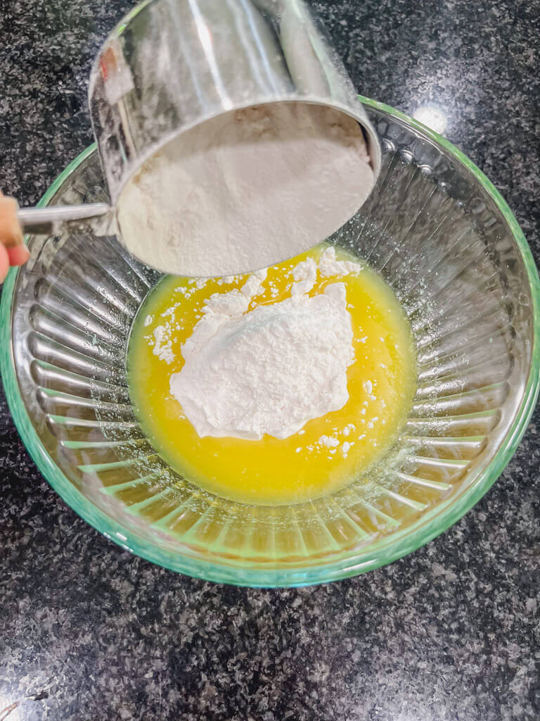 a cup of flour being added to the melted butter.