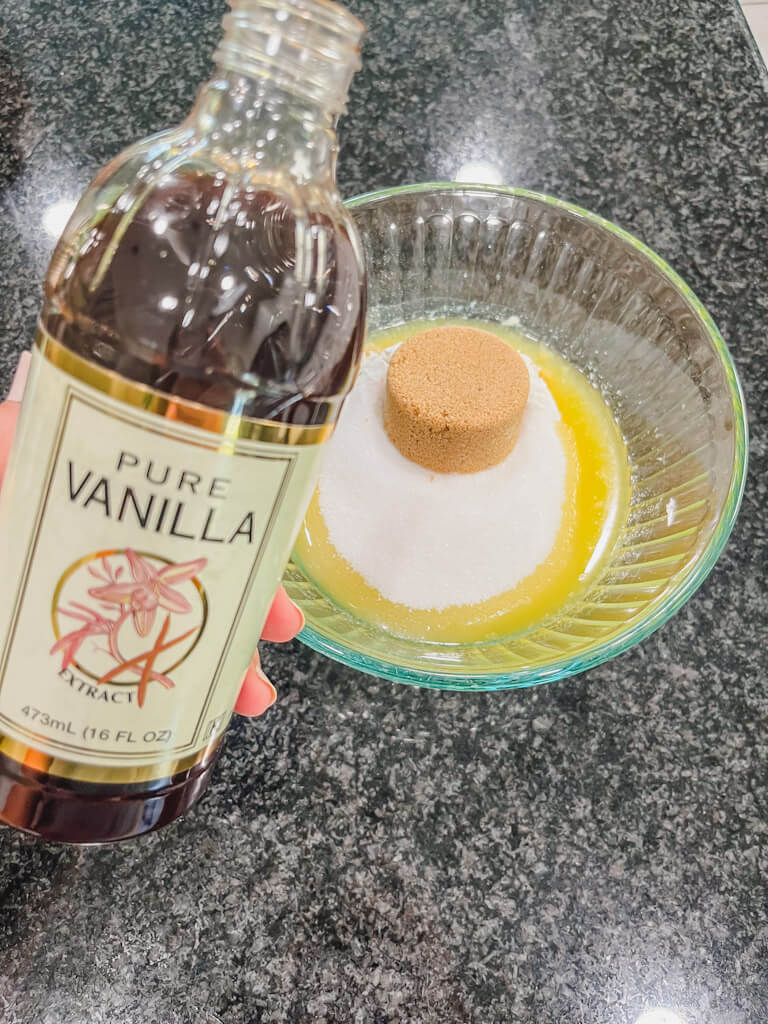 a bottle of vanilla extract being held over the bowl.