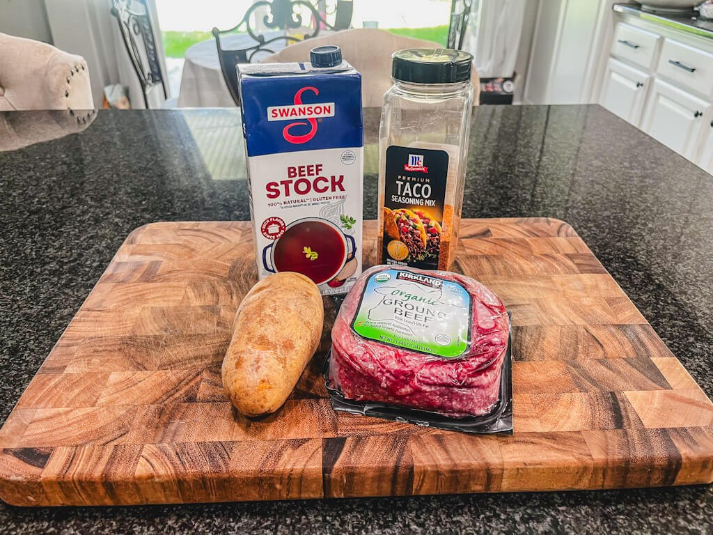 ingredients for beef and potato burritos on a wooden cutting board.