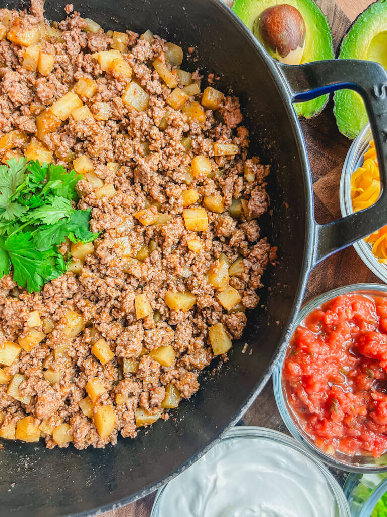 overhead view of a cast iron skillet with salsa and avocados next to the skillet.