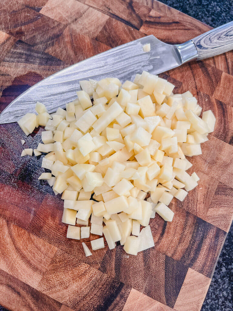 diced potatoes on a wooden cutting board.