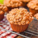 close up picture of a pumpkin apple streusel muffin on a wire rack.