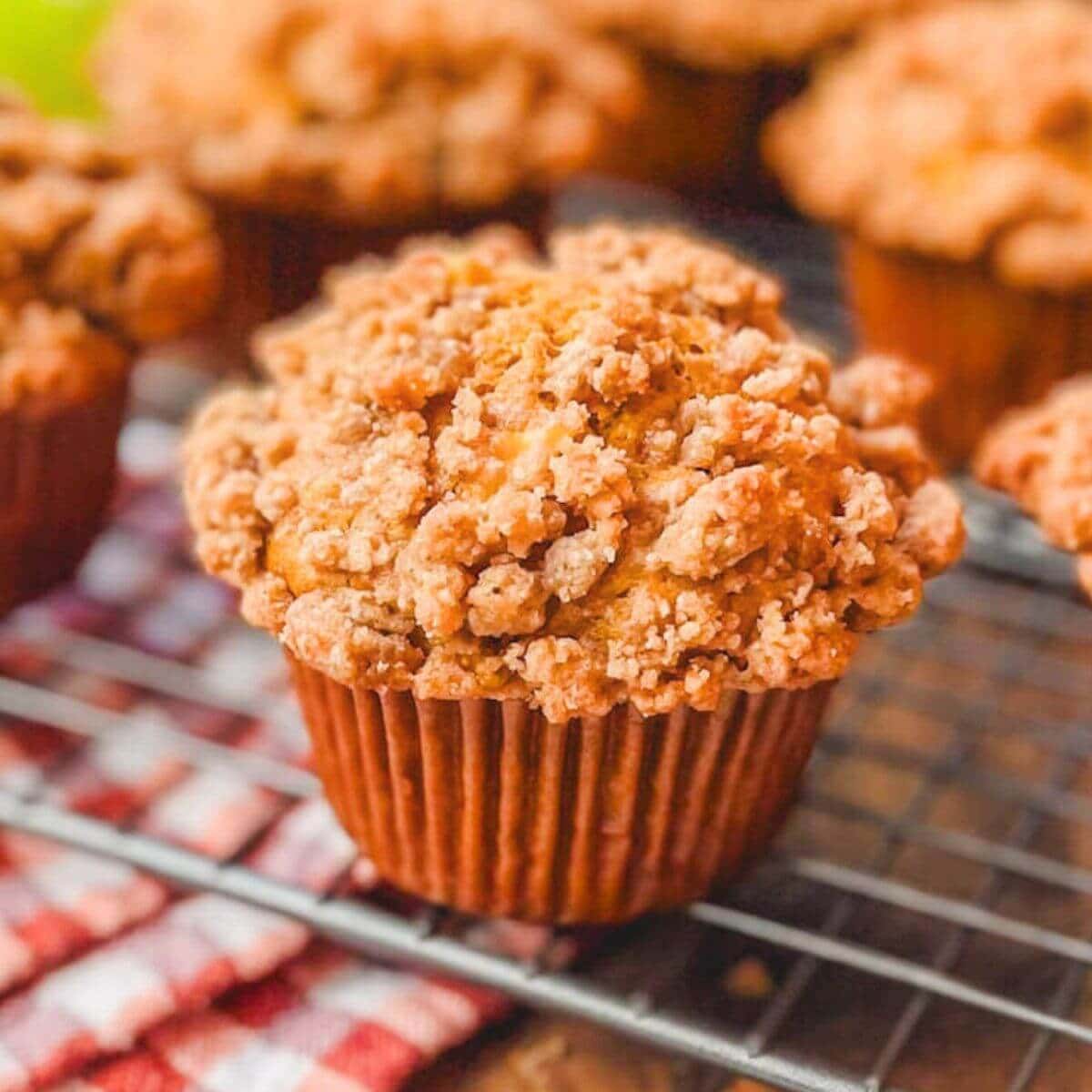 close up picture of a pumpkin apple streusel muffin on a wire rack.