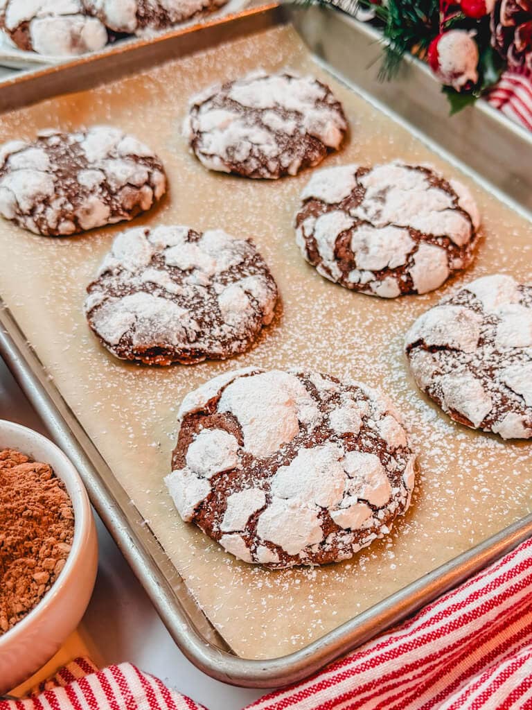 side angle view of 6 cookies on a cookie sheet that have been dusted with more powdered sugar.