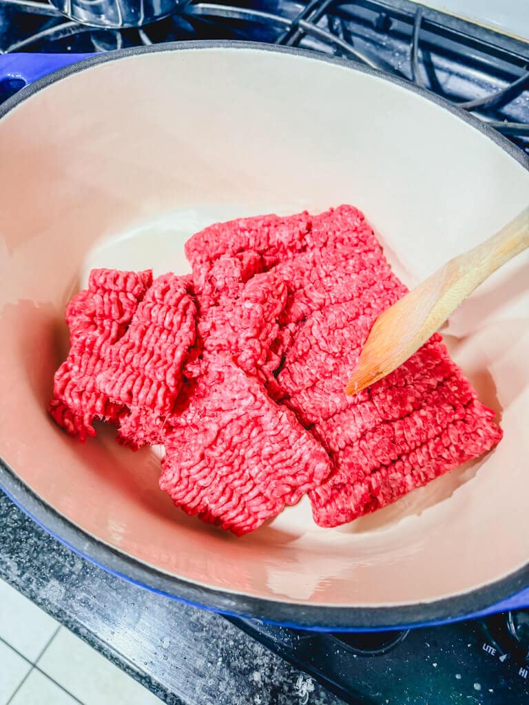 ground beef about to be browned in a large Dutch oven.