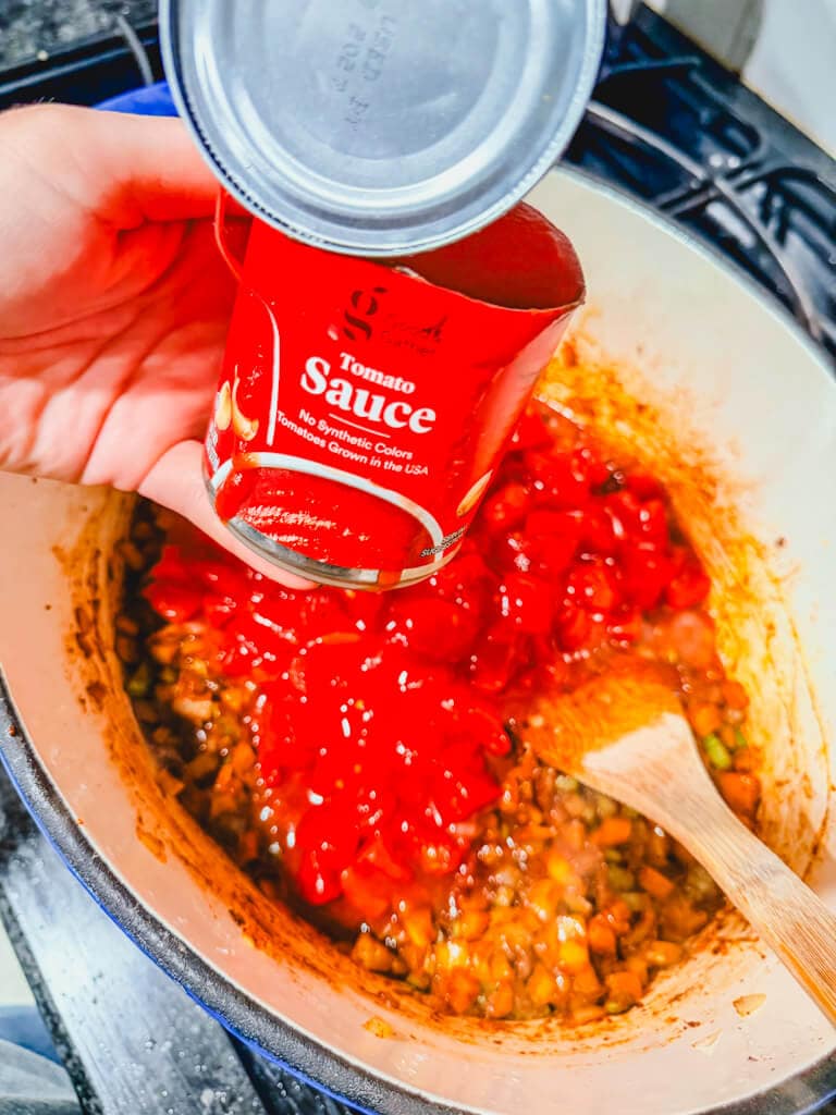 A small can of tomato sauce about to be added to the pot.
