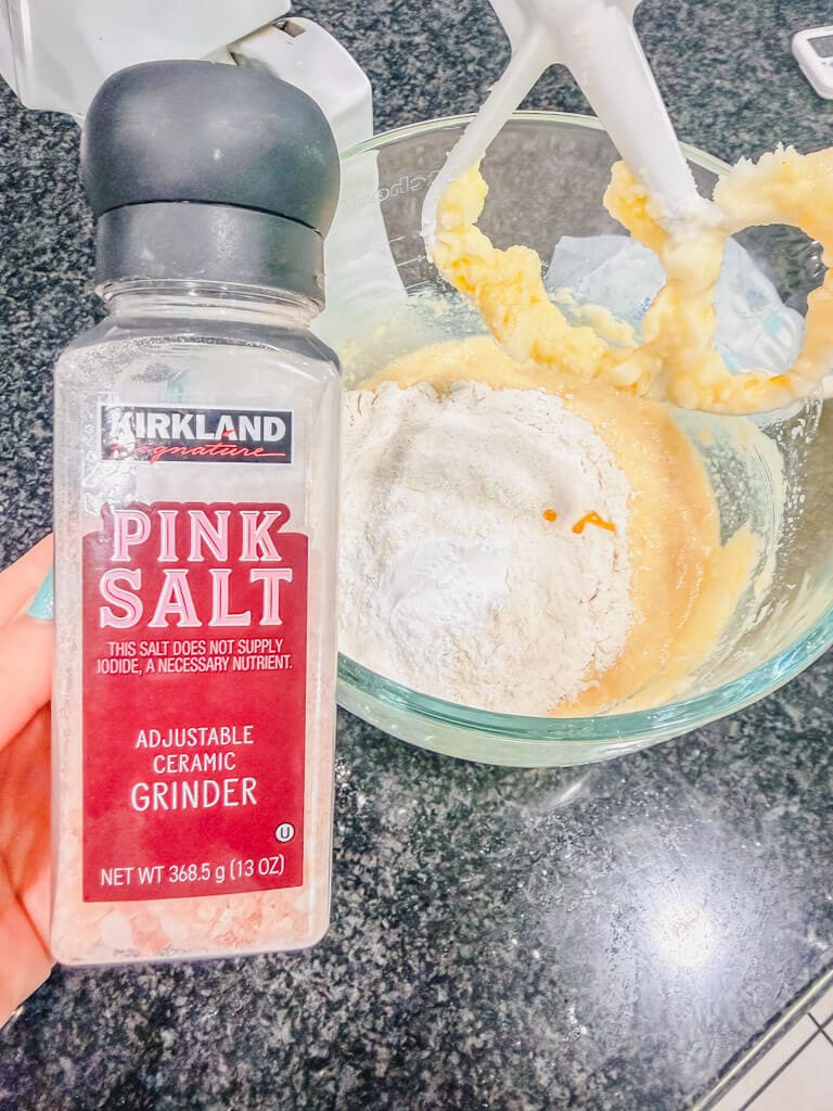 A bottle of salt being held over the mixing bowl.