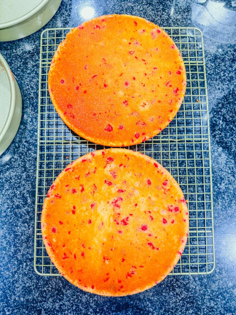 Cherry Chip cakes cooling on a wire rack on a black counter.