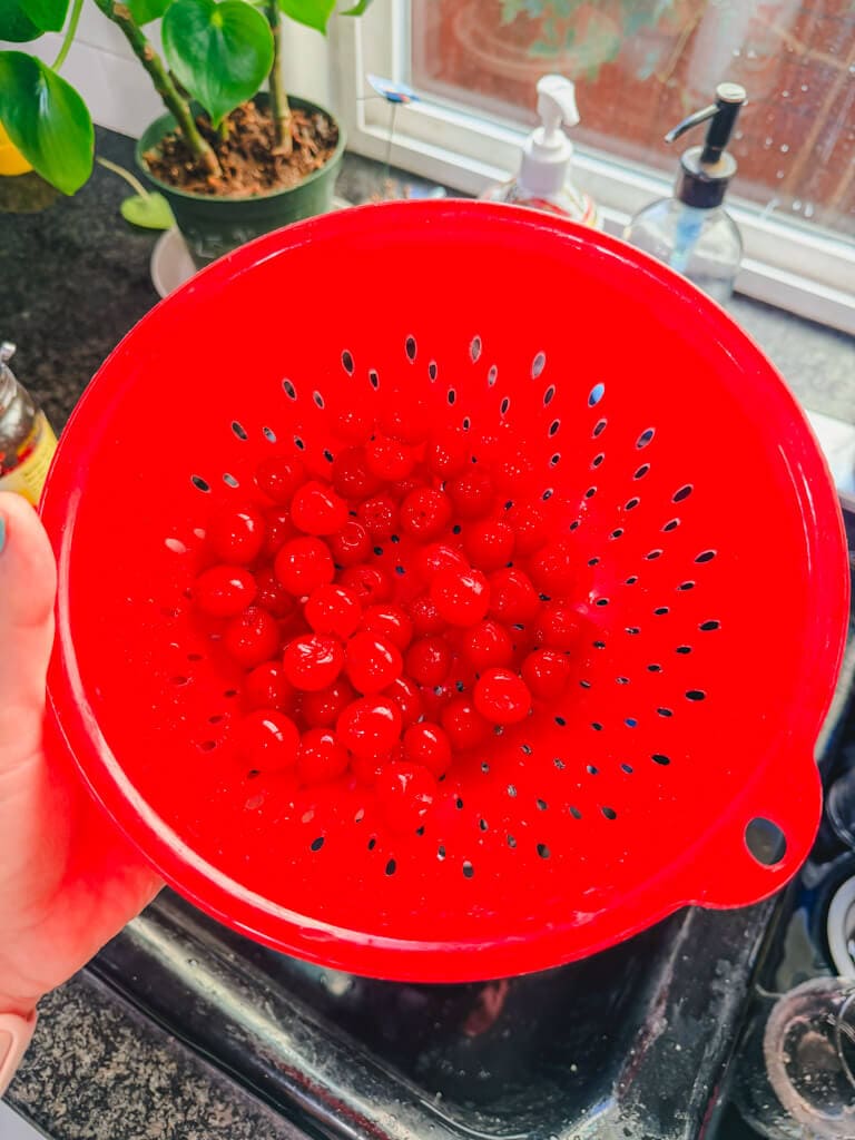 maraschino cherries in a red colander that have been rinsed.