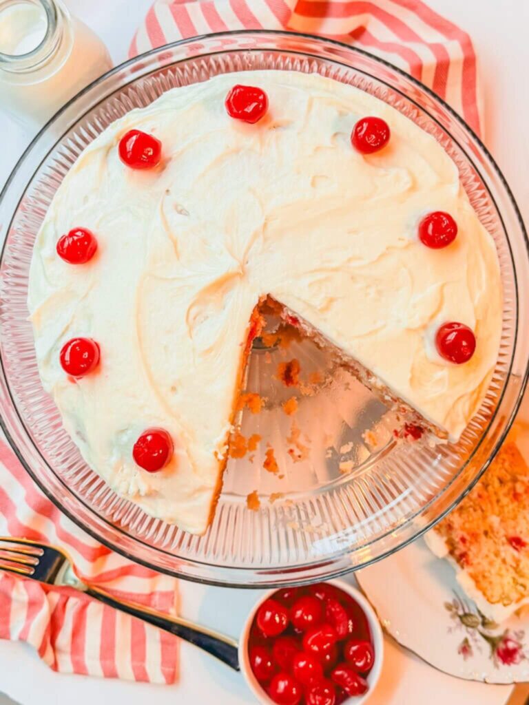 overhead view of Cherry Chip Cake on a cake stand next to a small bow of cherries.