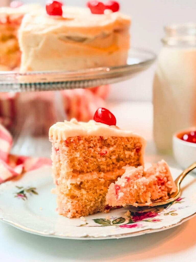 a slice of cherry chip cake on a plate with a fork-full of cake on a fork.