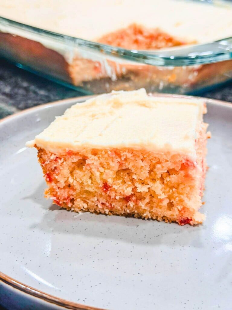 Betty Crocker Cherry Chip Cake baked in a 13" baking pan and a slice was taken out and put on a plate.