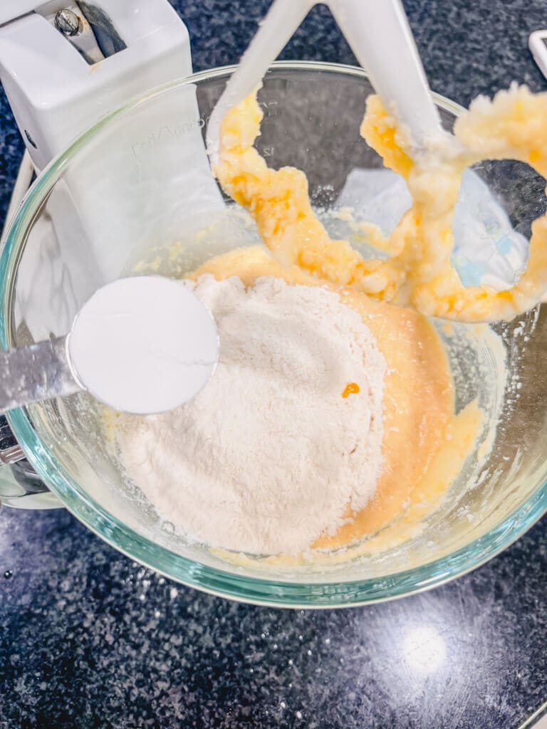a tablespoon of baking powder being held over the bowl.