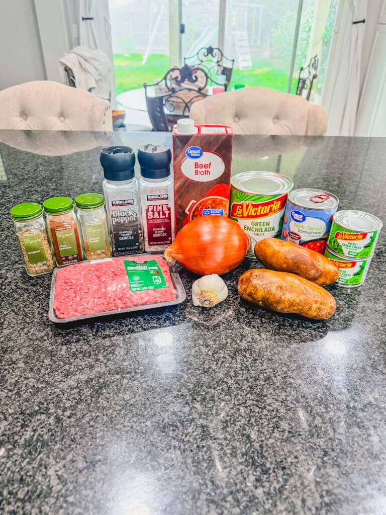 ingredients for ground beef chile stew laid out on a black counter.