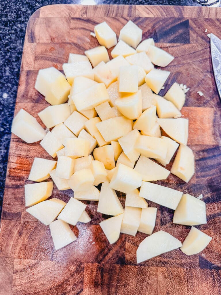 Russet potatoes that have been cubed on a cutting board ready to be added to the pot.
