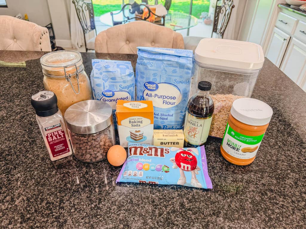 Ingredients for monster cookies with M&M's laid out on a black countertop.