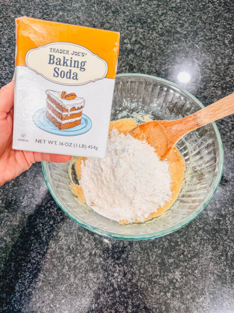 A box of baking soda being held over the mixing bowl.