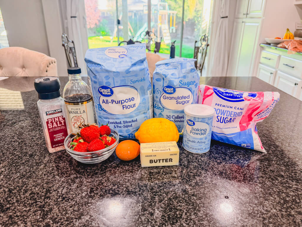 ingredients for strawberry lemon bars on a black countertop.
