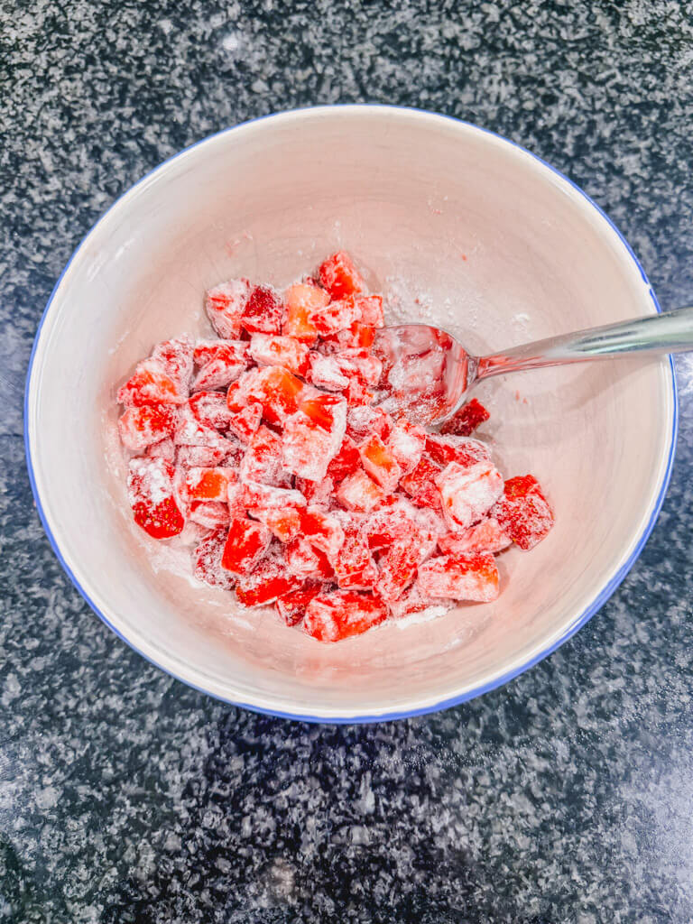 Flower sprinkled into the bowl of diced strawberries.