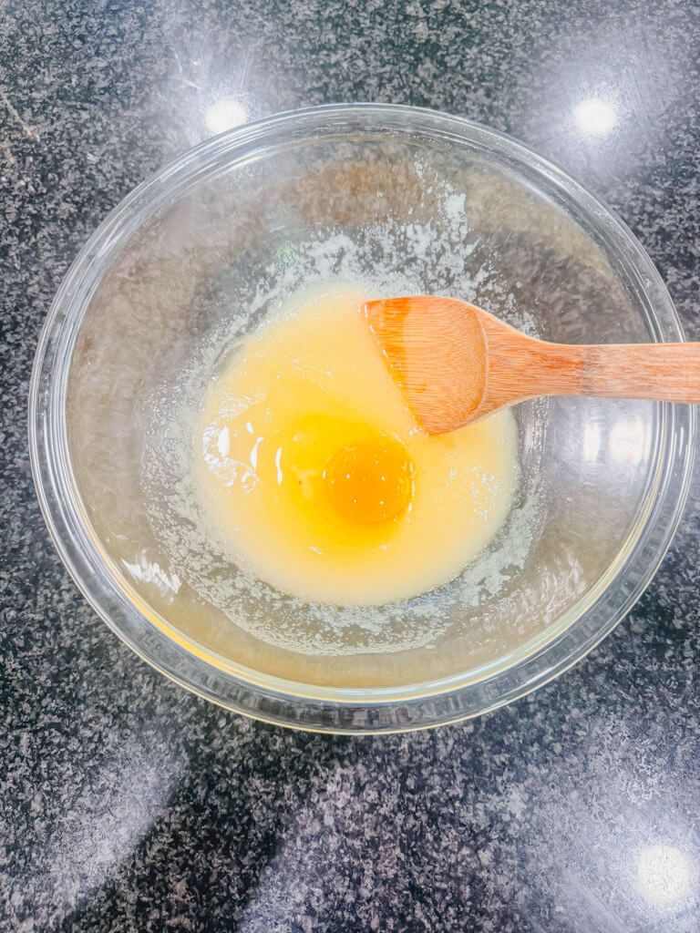 One room, temperature egg added to the mixing bowl of butter and sugar.