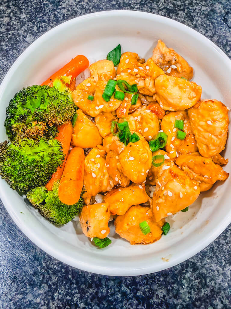 Overhead view of Teriyaki Chicken recipe in a white bowl with broccoli. 